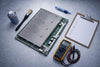 ASIC mining farm maintenance workstation with hashboard, cleaning tools, thermal paste, and a multimeter laid out for a quarterly inspection.
