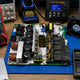 Open Bitmain APW17 1215a power supply with board-level components labelled and replacement parts on workbench — APW17 1215a repair components list