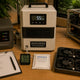 Top-down editorial photograph of a tropical mining operations workspace with industrial-grade dehumidifier showing 55% humidity reading.